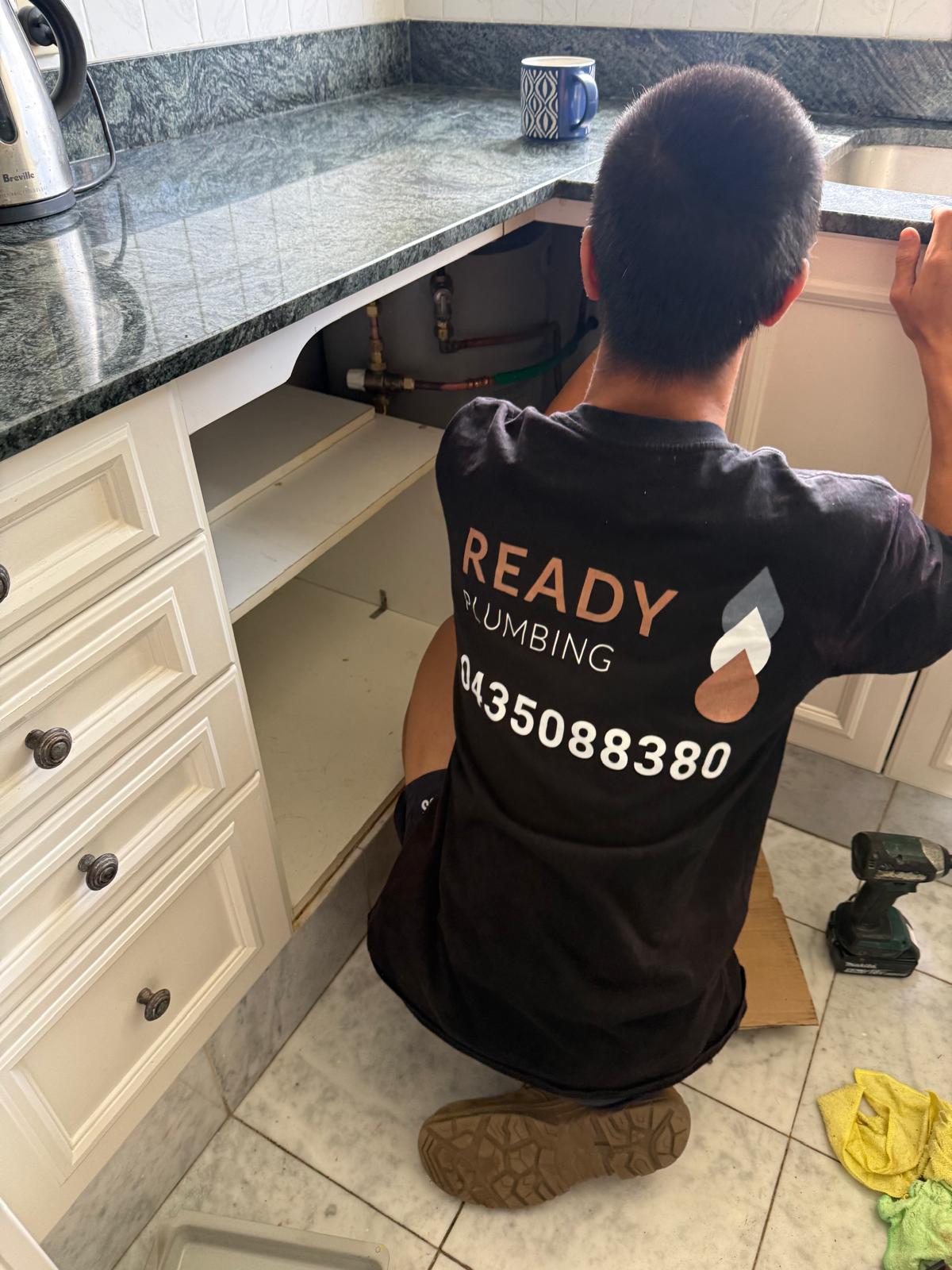 Inspecting the plumbing under a Cromer kitchen sink for the source of a slow leak